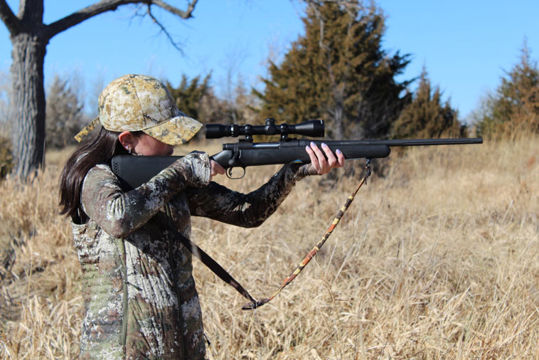 Campfire Collective Hunting Ambassador Chloe Annalcazar dressed in campuflage, taking aim with a bolt action rifle.