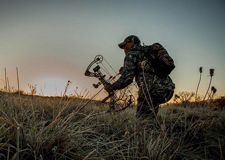 Chasseur avec un arc dans les hautes herbes au crépuscule