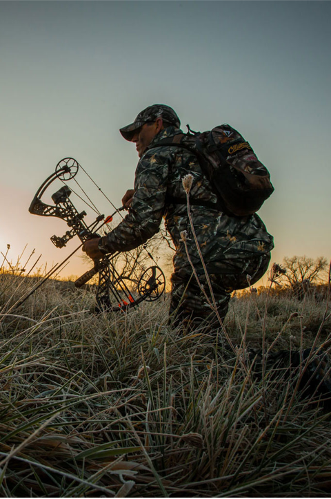 Chasseur avec un arc dans les hautes herbes au crépuscule