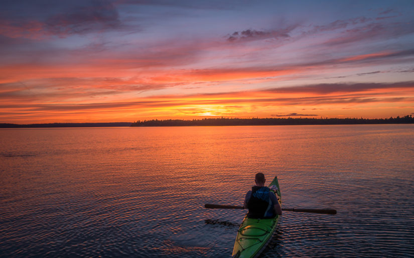 Campfire Collective Kayaking Ambassador Gordon Pusnik in his kayak on Kennisis Lake at sunset.