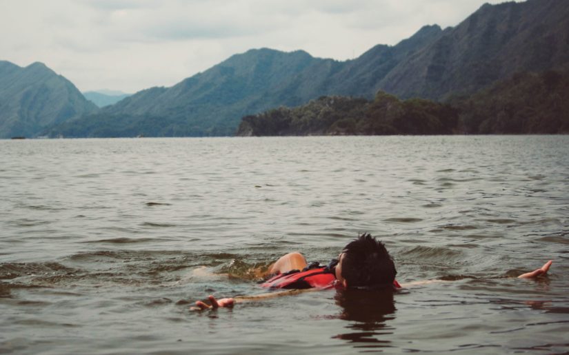 Boater wearing lifejacket, floating face-up in water.