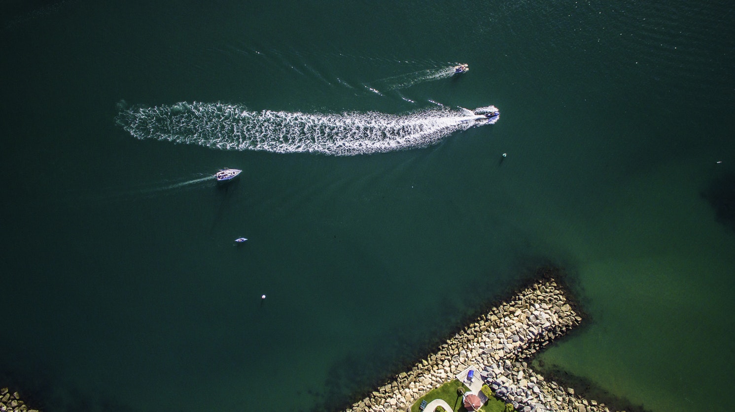 Aerial view of powerboats and personal  watercraft (PWC) on aqua-colored water.