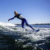 Wakesurfer wearing cold-water wetsuit, surfing the wake behind a boat.