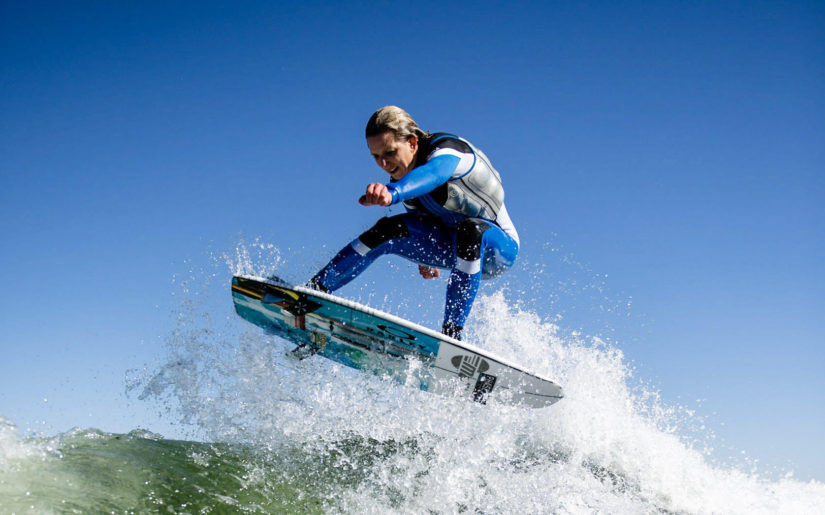 Campfire Collective Wakesurfing Ambassador Stacia Bank jumping a wake behind boat.