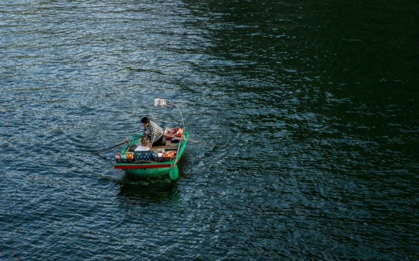 Woman stnading up in a small row boat.