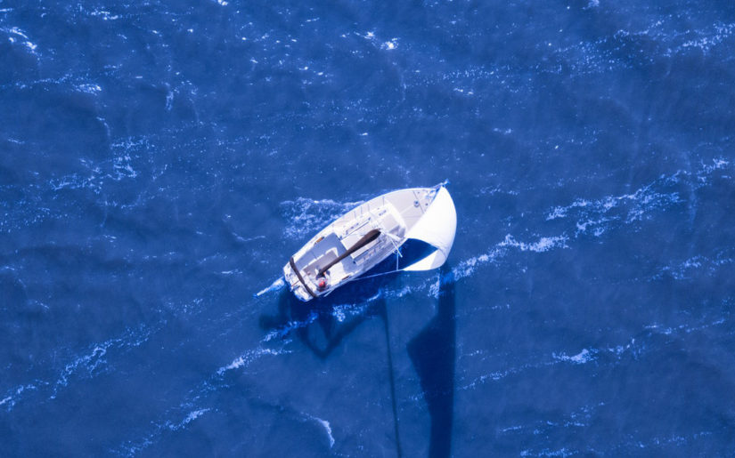 Aerial view of sailboat racing through blue waters.