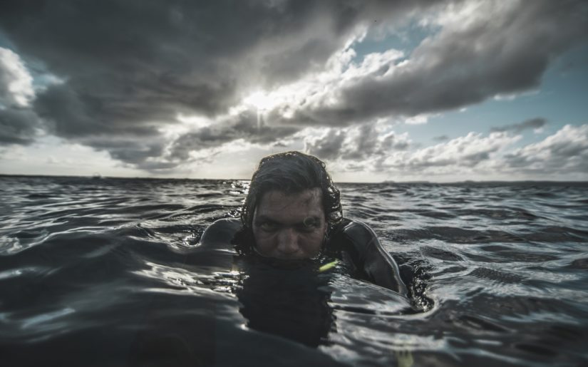 Boater in the water wearing inflatable personal flotation device after abandoning ship.