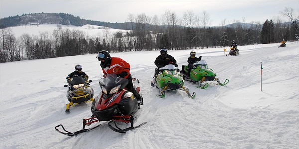 Six snowmobilers on a trail in New York.