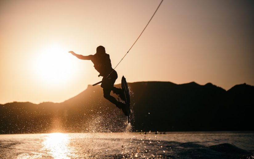 Wakeboarder performing a trick over the wake behind a boat.