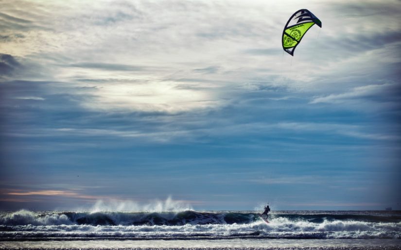 Kit surfer riding the wave on the ocean coast.