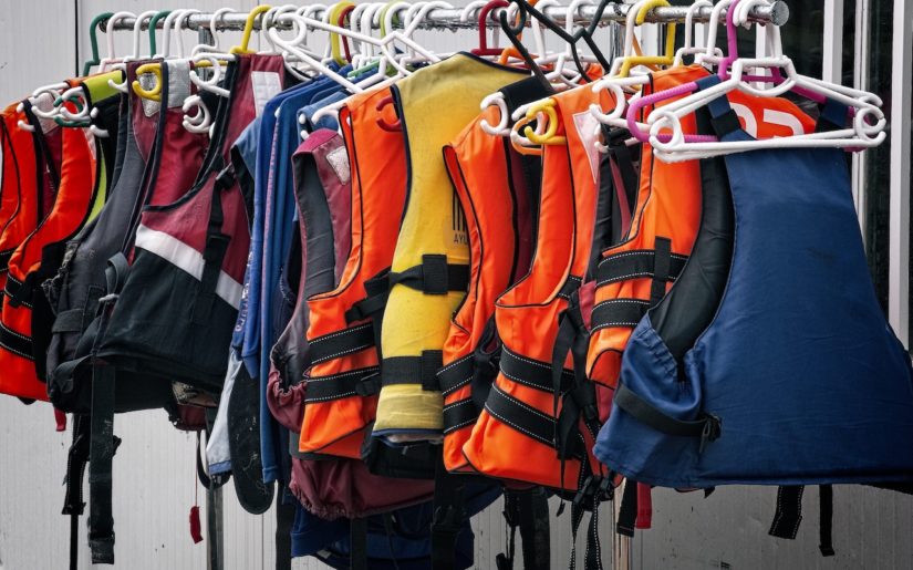 Colourful lifejackets hangings on a rack.