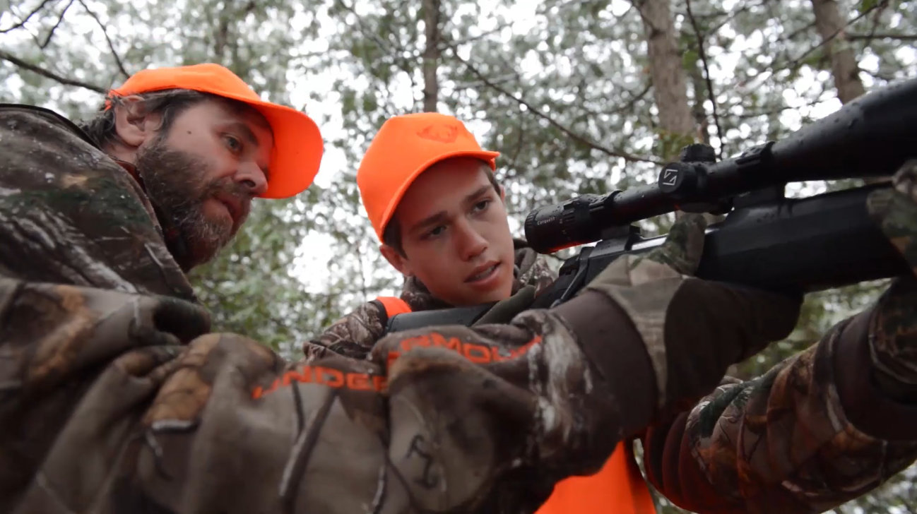 Dad showing son how to use a rifle