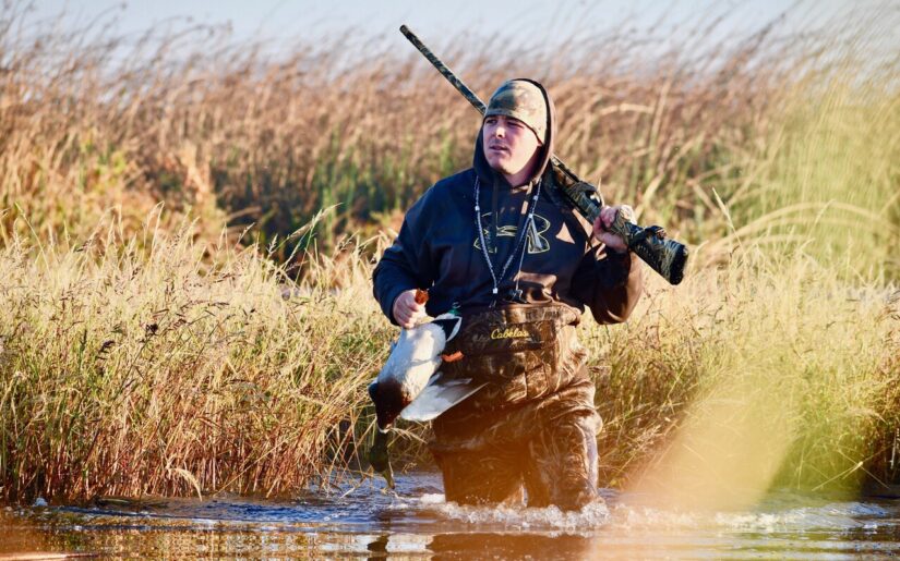 Duck hunter carrying bird